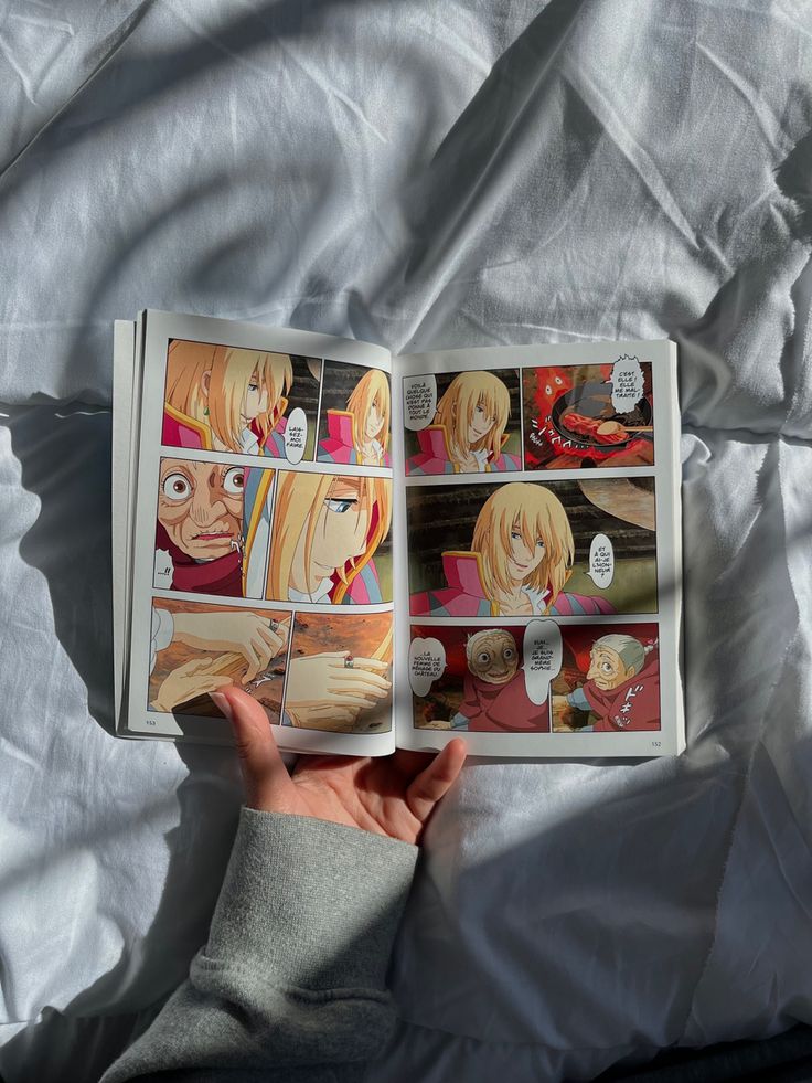 an open book with pictures of people in it on a white sheeted bed spread