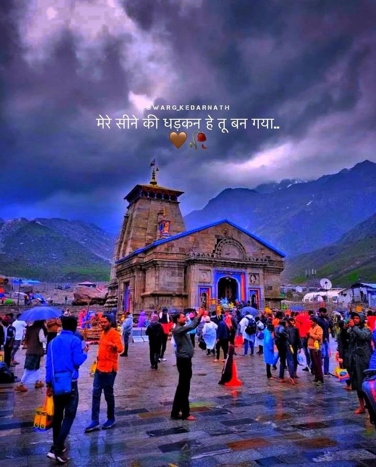 many people are standing in front of a building with mountains in the background and an overcast sky