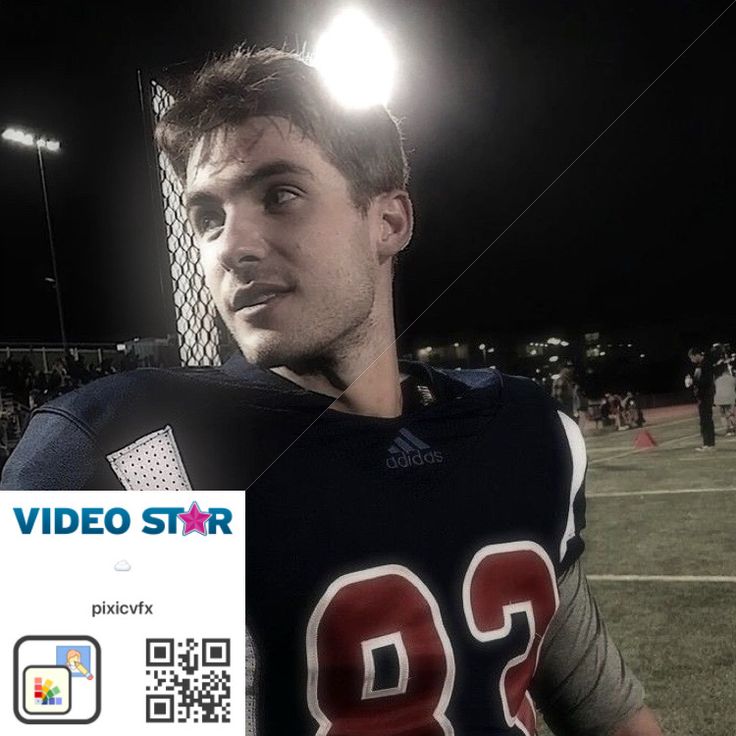 a young man in a football uniform standing on a field at night with lights behind him