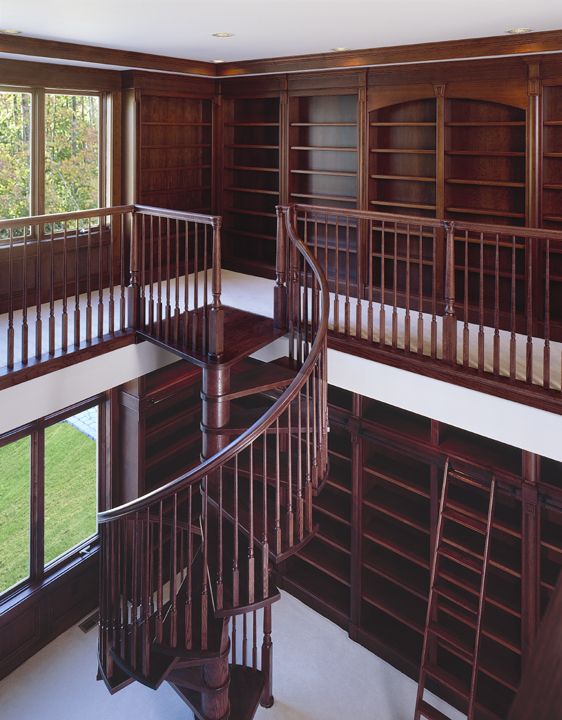 a spiral staircase in the middle of a room with bookshelves on both sides