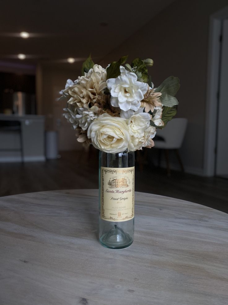 a vase filled with flowers sitting on top of a table next to a wine bottle