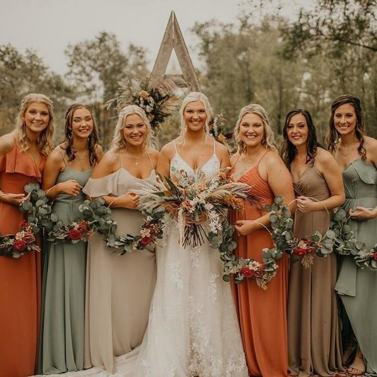 a group of women standing next to each other wearing dresses and holding bouquets in their hands