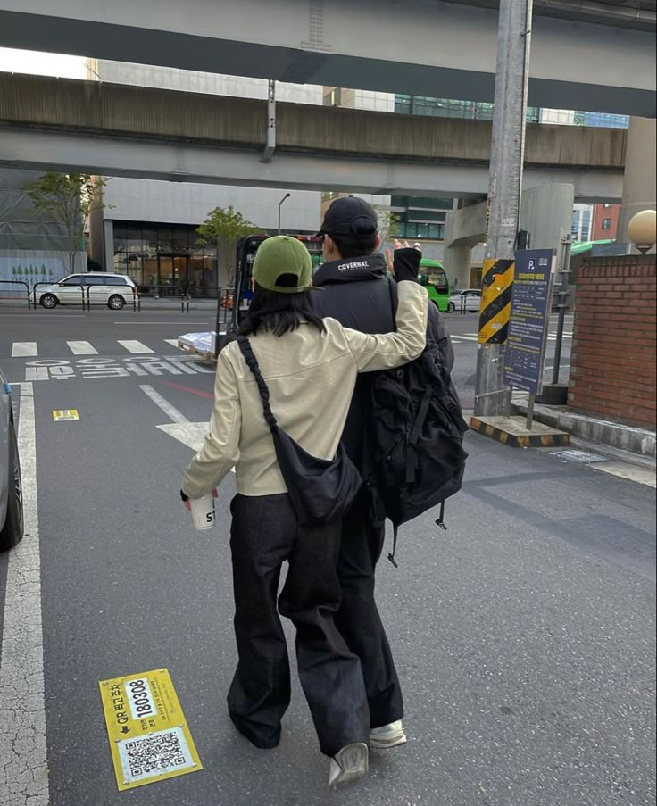 two people walking down the street with backpacks on their backs and one person holding onto another man's back