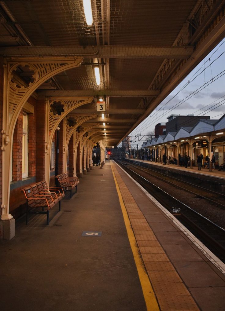 an empty train station with people waiting on the platform