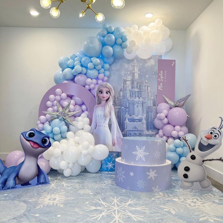 a frozen princess themed birthday party with balloons, cake and figurines on the table