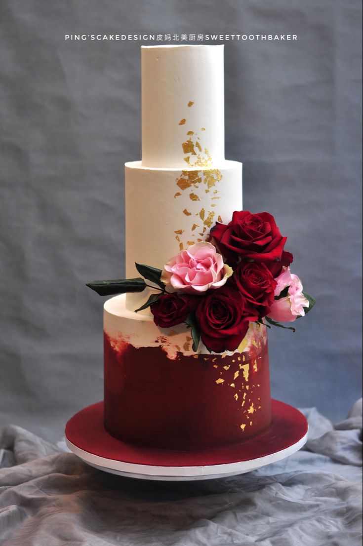 a white and red wedding cake with flowers on top