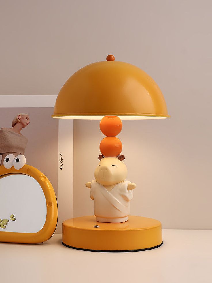 a yellow lamp and mirror sitting on a table next to each other with an odd looking object in front of it