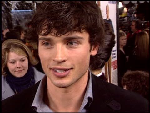 a close up of a person talking on a red carpet with people in the background