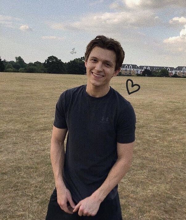 a man standing in a field with a heart drawn on the grass above his head