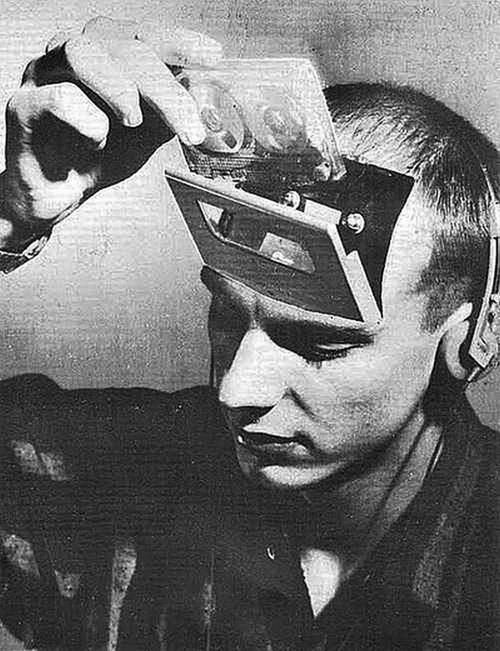 a black and white photo of a man with his head covered in electronic gadgets