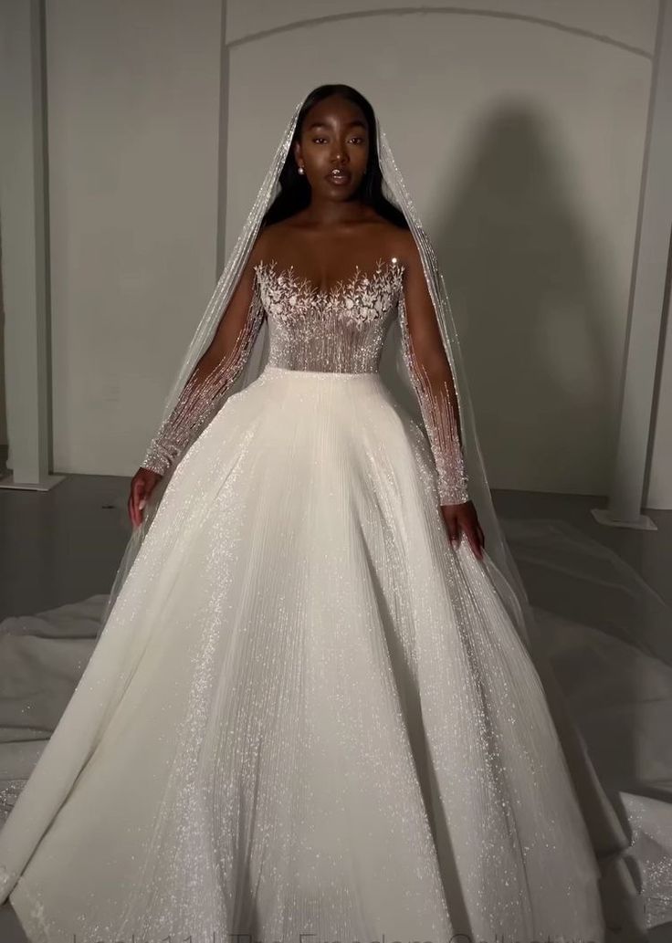 a woman in a white wedding dress with long sleeves and a veil on her head