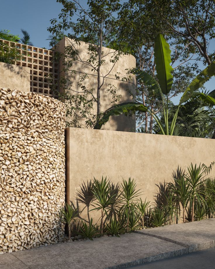 a concrete wall with plants and trees in the back ground, next to a sidewalk