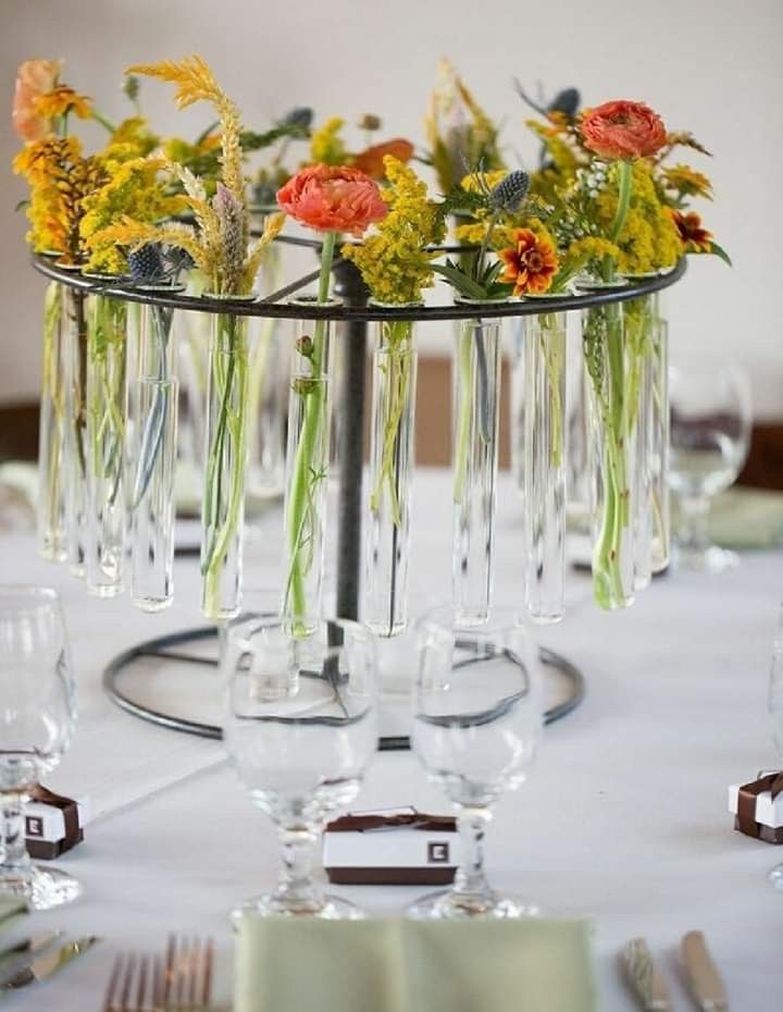 there are many flowers in the vases on this table clothed place setting with silverware