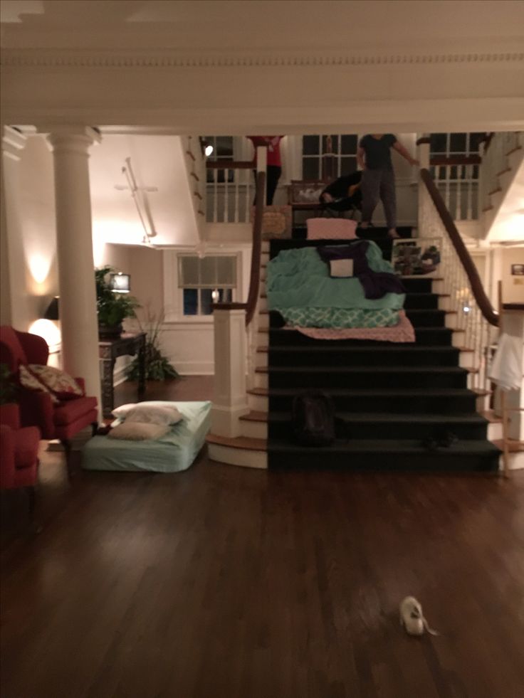 a person standing on top of a stair case next to a couch and chair in a living room