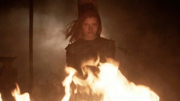 a woman standing in front of fire with her hair blowing back and eyes closed,