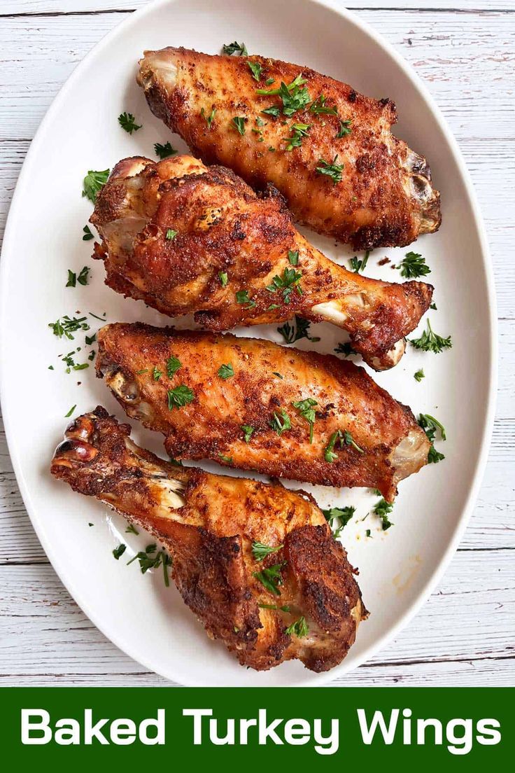 baked turkey wings on a white plate with parsley garnish and the words baked turkey wings