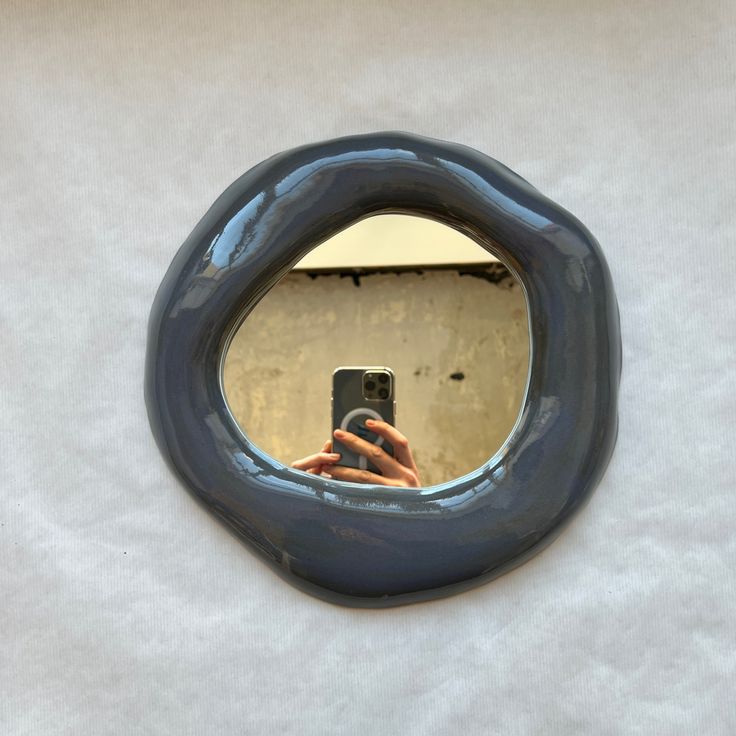 a person taking a selfie in front of a round mirror on a white wall