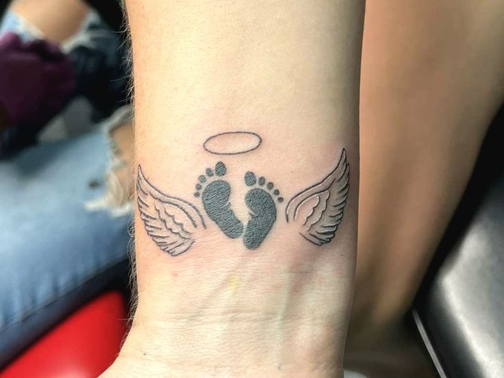 a woman's foot with two wings and an angel wing tattoo on her wrist