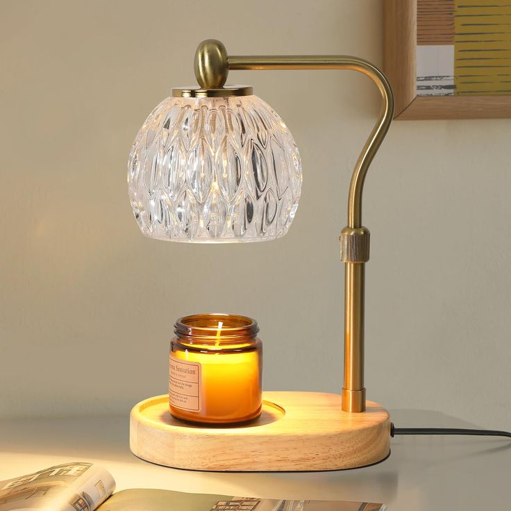 a table lamp with a jar on it next to an open magazine and a candle