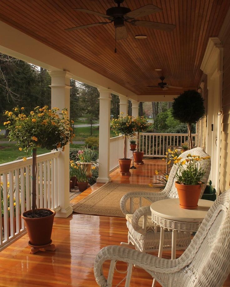 a porch with wicker chairs and potted plants on the front porch, next to a wooden floor