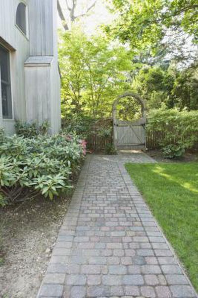 a brick walkway leading to a white house