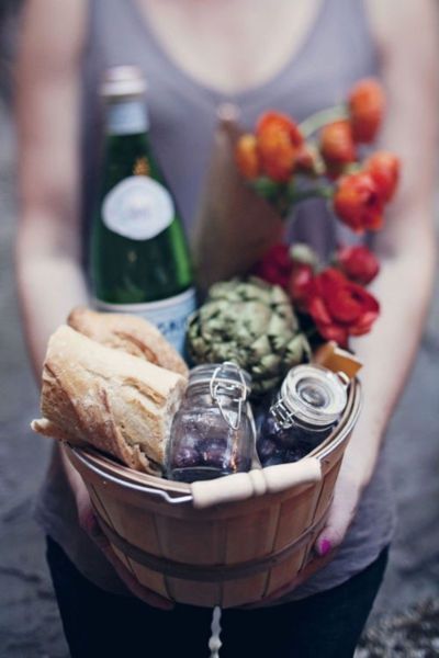 a woman holding a basket filled with food and drinks