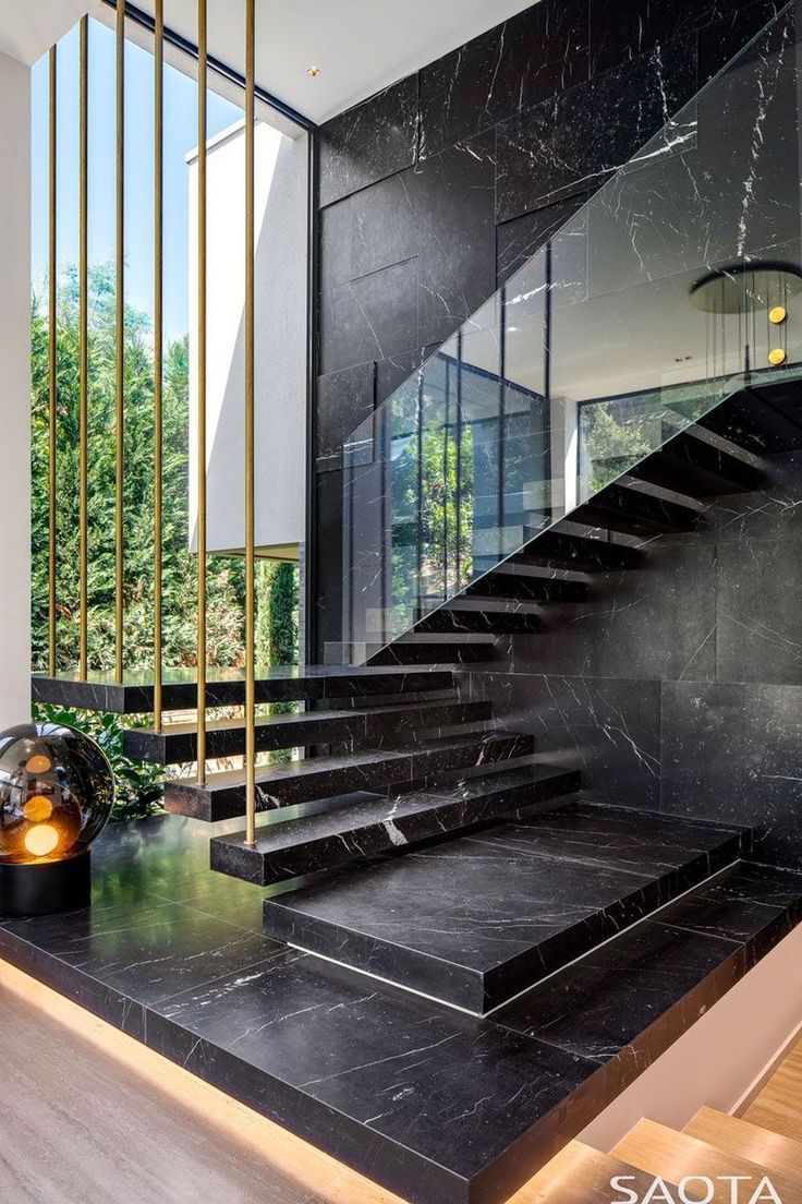 a black marble staircase leading up to the second floor in a modern house with gold accents