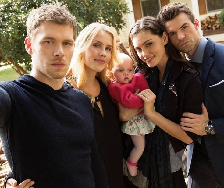 the cast of modern family posing for a photo in front of a house with their arms around each other