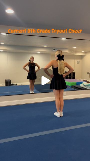 a girl in a black dress is standing on a blue floor with her hands behind her back