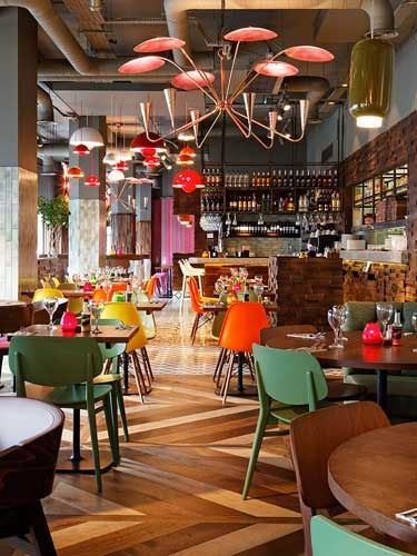 the interior of a restaurant with many tables and chairs, lights hanging from the ceiling