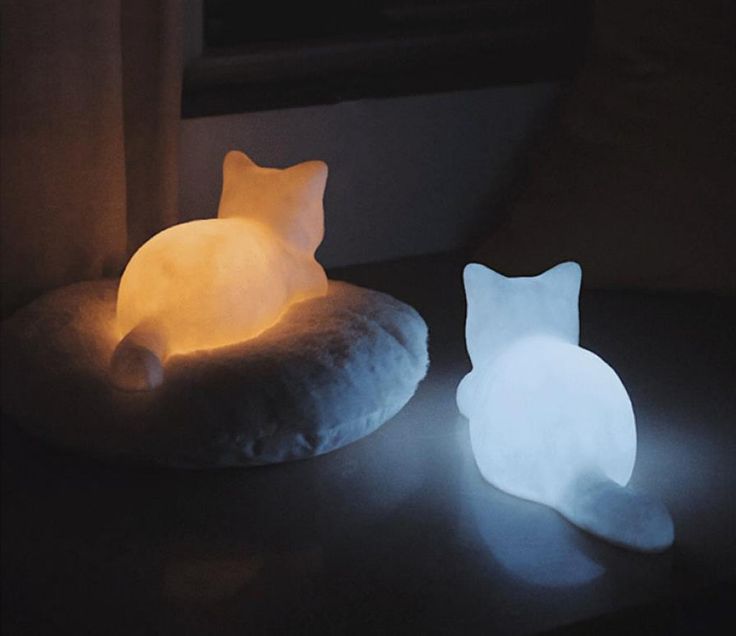 a cat shaped pillow sitting on top of a table next to a lit up light