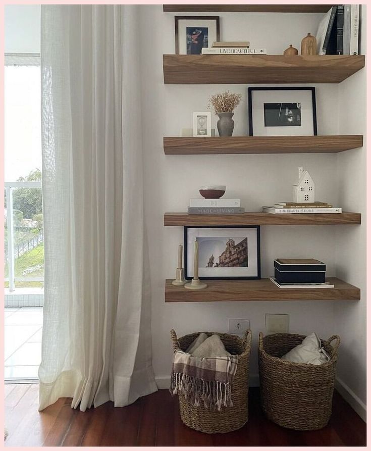 three wooden shelves with pictures, books and other items on them in front of a window