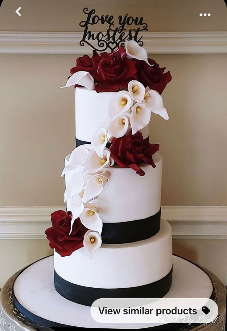 a white and black wedding cake with red flowers