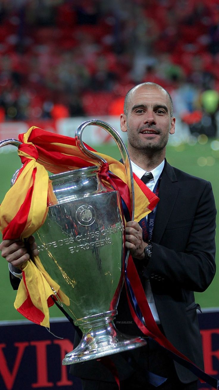 a man in a suit holding a soccer trophy