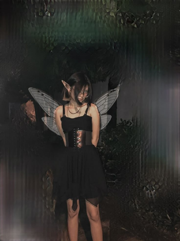 a woman wearing a corset standing in front of a wall with a fairy wings on it