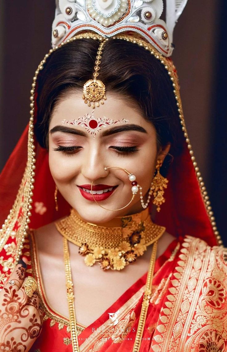 a woman wearing a red and gold bridal outfit with a crown on her head