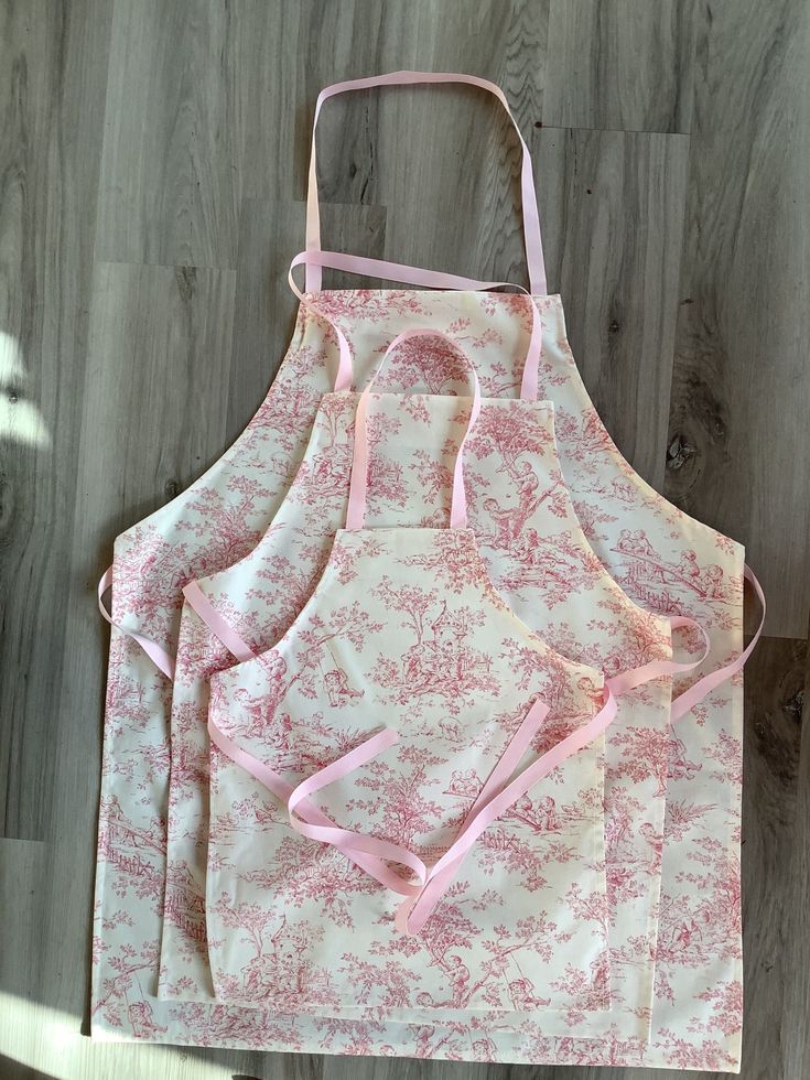 three pink aprons sitting on top of a wooden floor