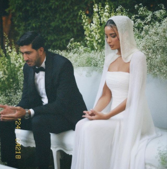 a bride and groom sitting on a bench