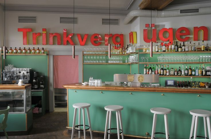 the interior of a restaurant with green walls and stools in front of the counter