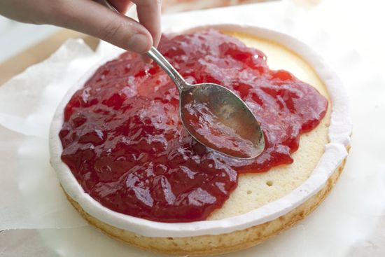 a person spooning ketchup onto a piece of bread