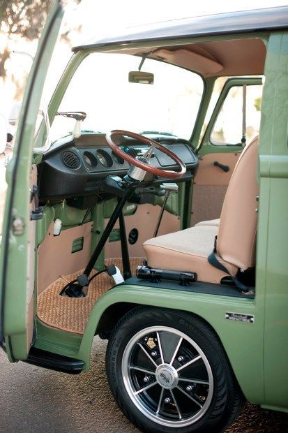 the interior of an old green truck with its door open and steering wheel in view