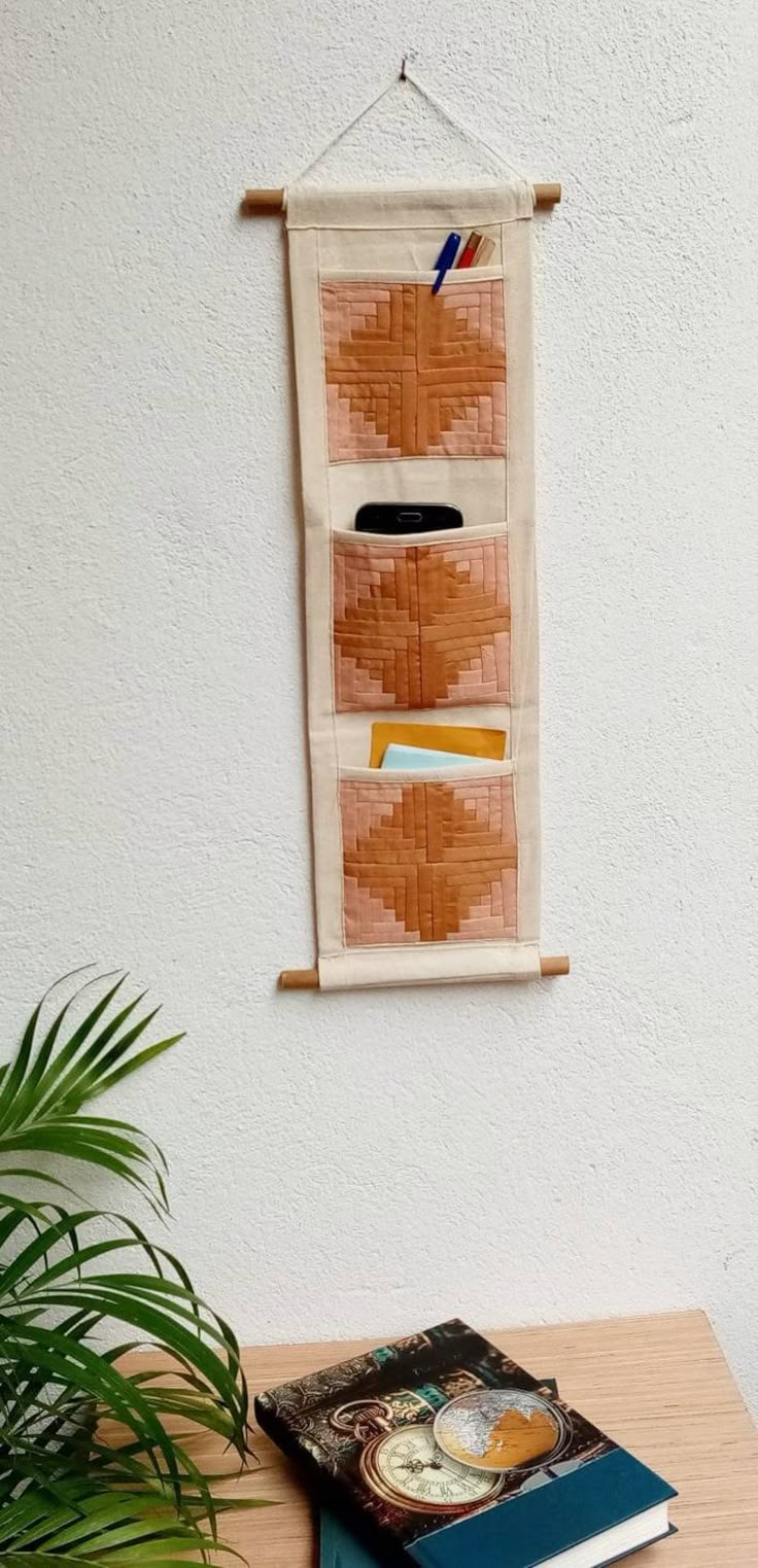 a wooden table topped with a book next to a potted plant and a wall hanging