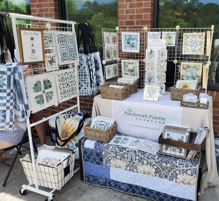 quilts and cards are on display in front of a window at patchwork pottery