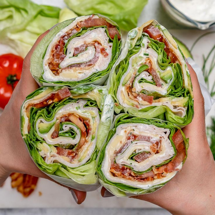 there are many wraps on the plate with lettuce and tomatos in the background