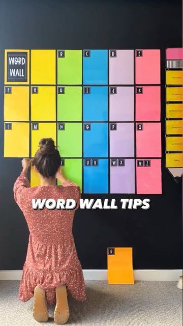 a woman sitting on the floor in front of a colorful wall with words written on it