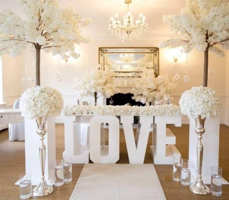 a table with flowers and candles on it in the middle of a room that says love