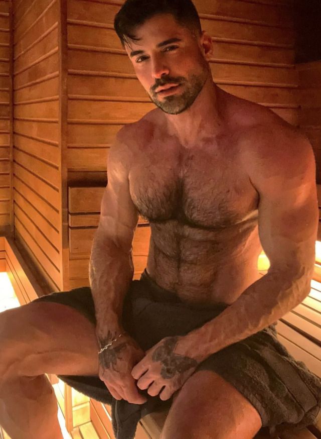 a shirtless man sitting in a sauna with his legs crossed and no shirt on