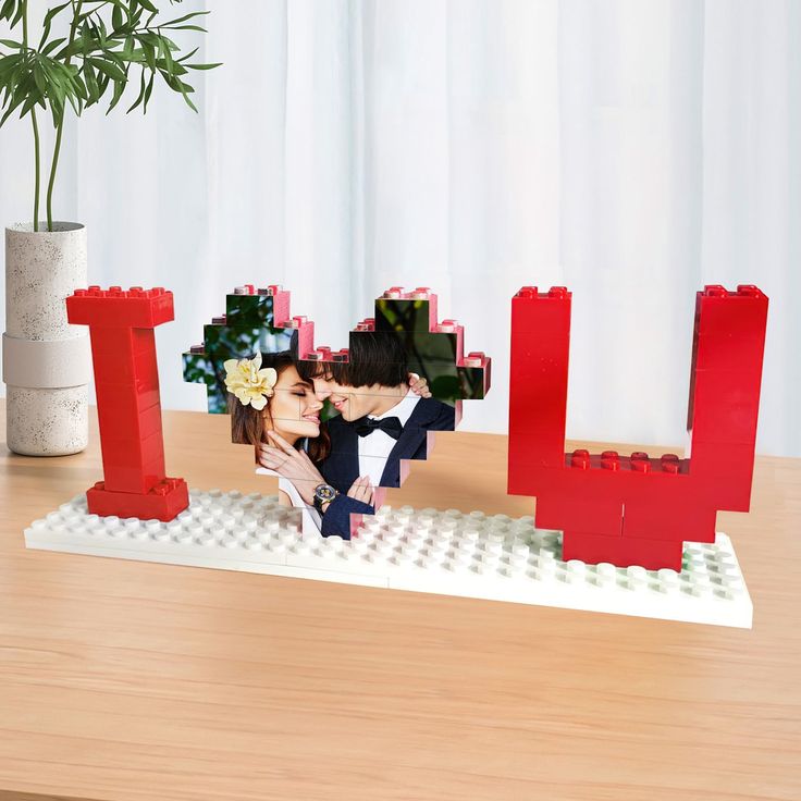 a couple kissing in front of the word love made out of legos on a table