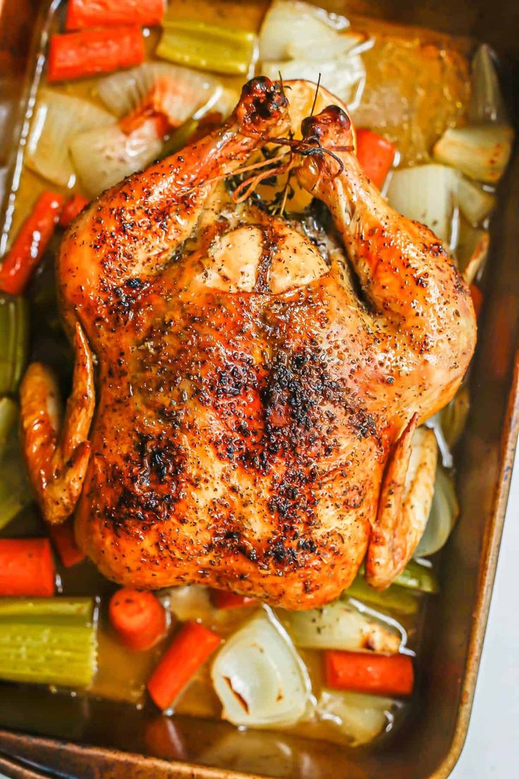 a roasting pan filled with chicken, carrots and celery