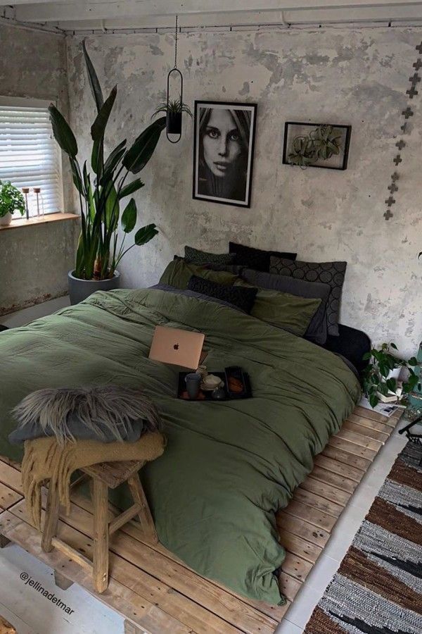 a bed sitting on top of a wooden floor next to a plant in a pot